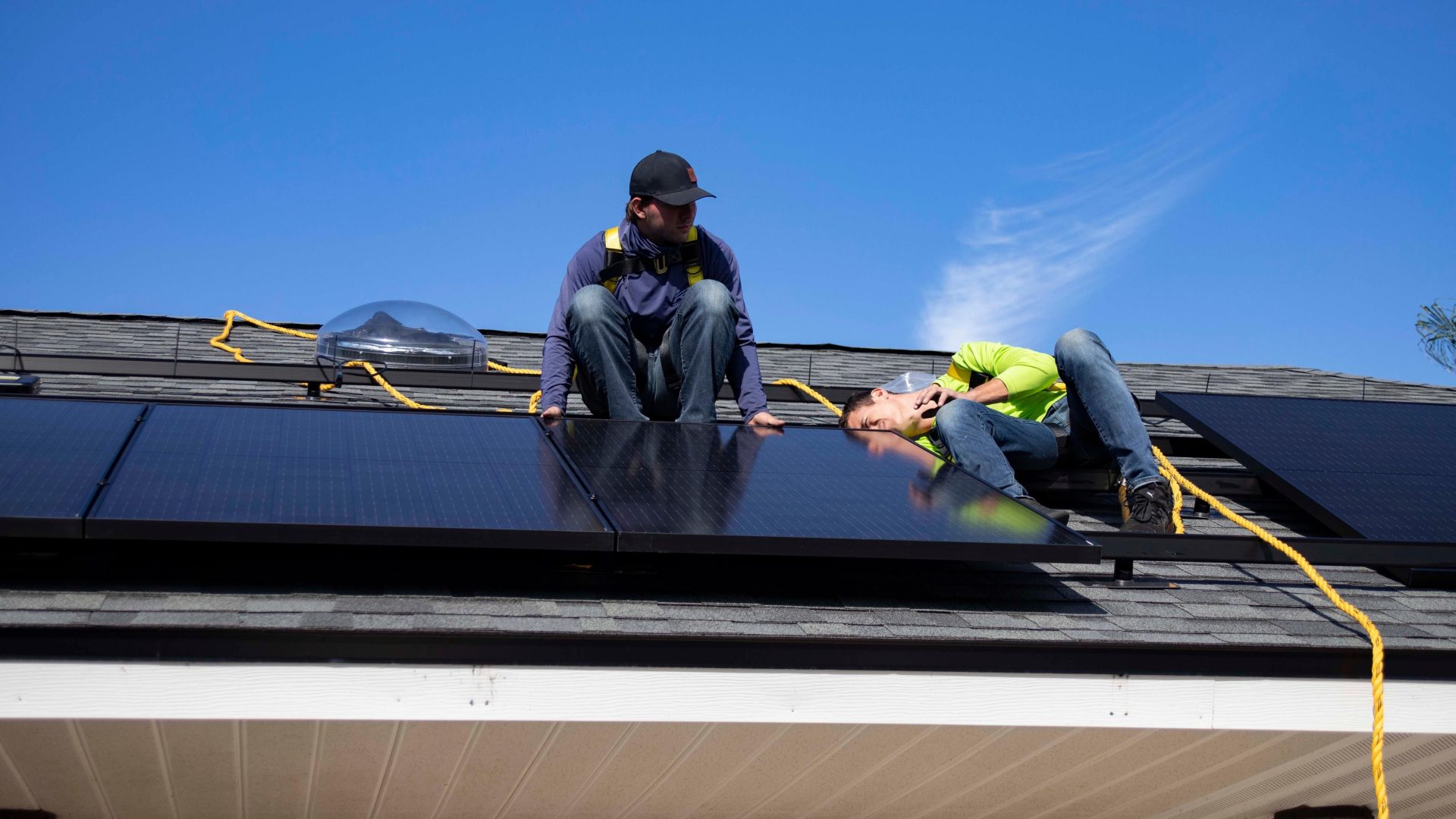Arbeiter installieren bei klarem Himmel Solarmodule auf einem Dach in St. Augustine.