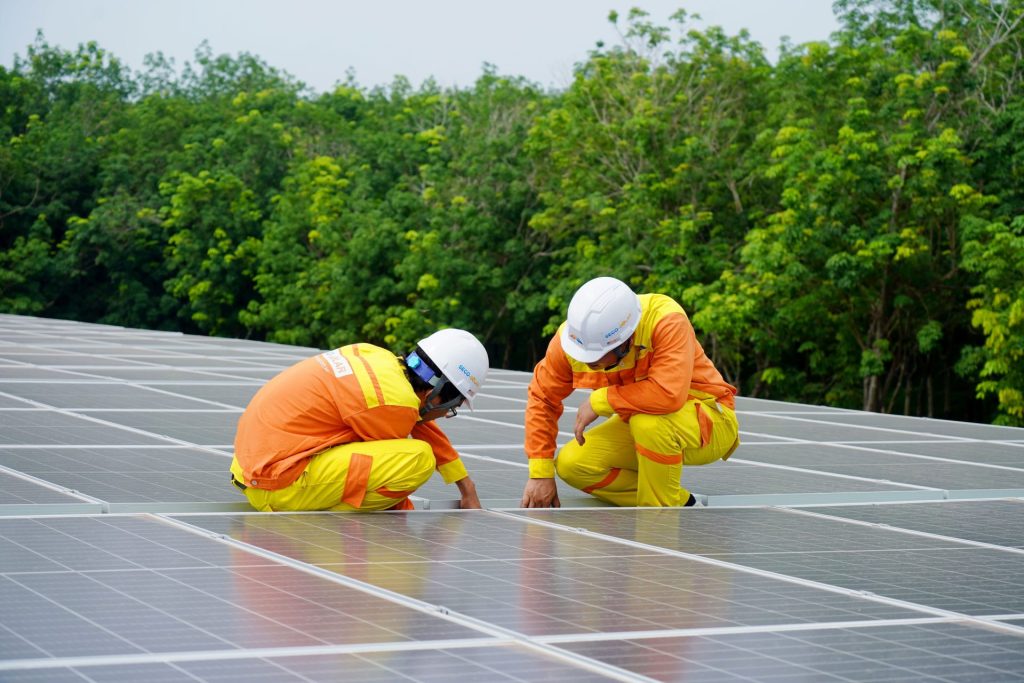 Arbeiter installieren bei klarem Himmel Solarmodule auf einem Dach in St. Augustine.