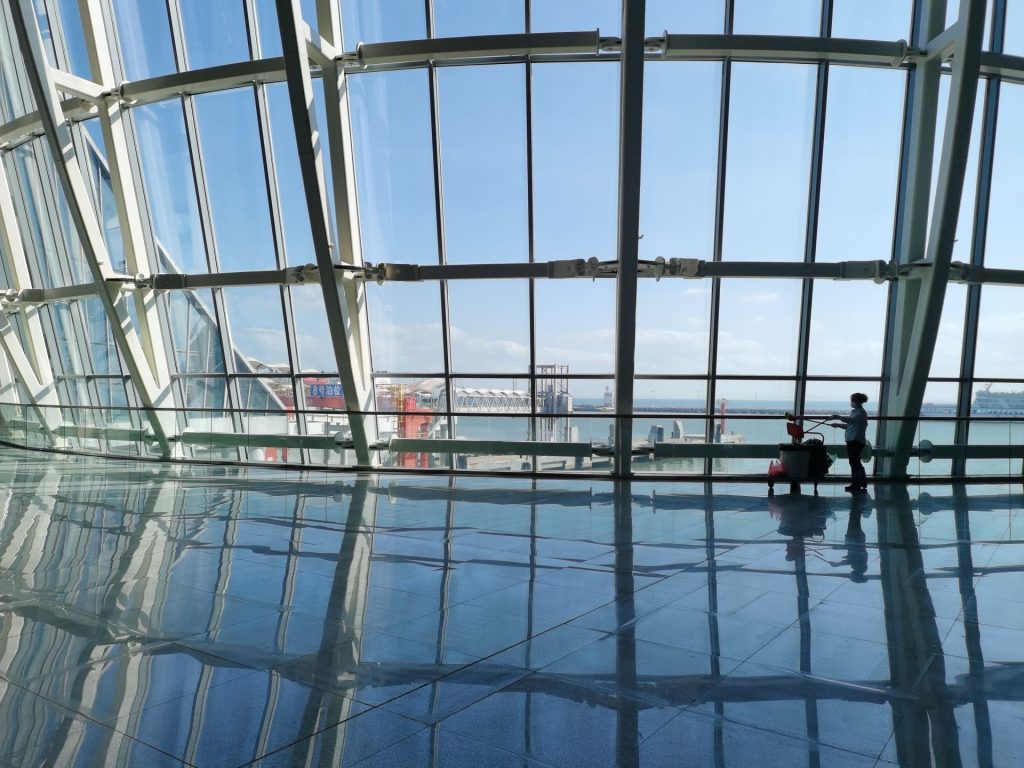 Ein geräumiges Hafenterminal mit großen, spiegelnden Fenstern und Blick auf das Meer.
